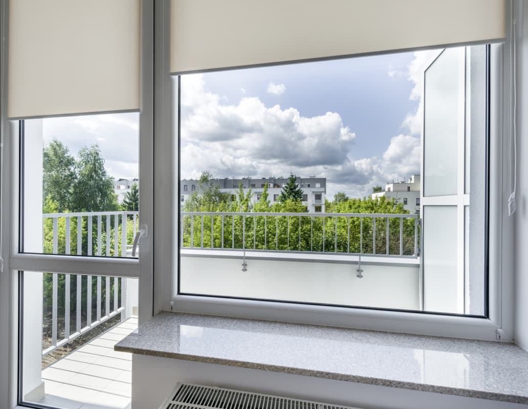 Ein Fenster mit Jalousien, das einen Blick nach draußen auf die Umgebung bietet.