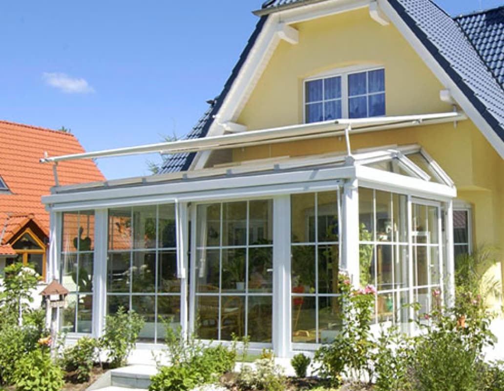 Ein Haus mit einer großen, verglasten Veranda, die viel Licht und einen Blick auf die Umgebung bietet.