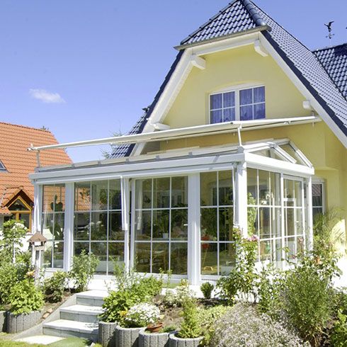 Ein gelbes Haus mit weißen Wintergarten